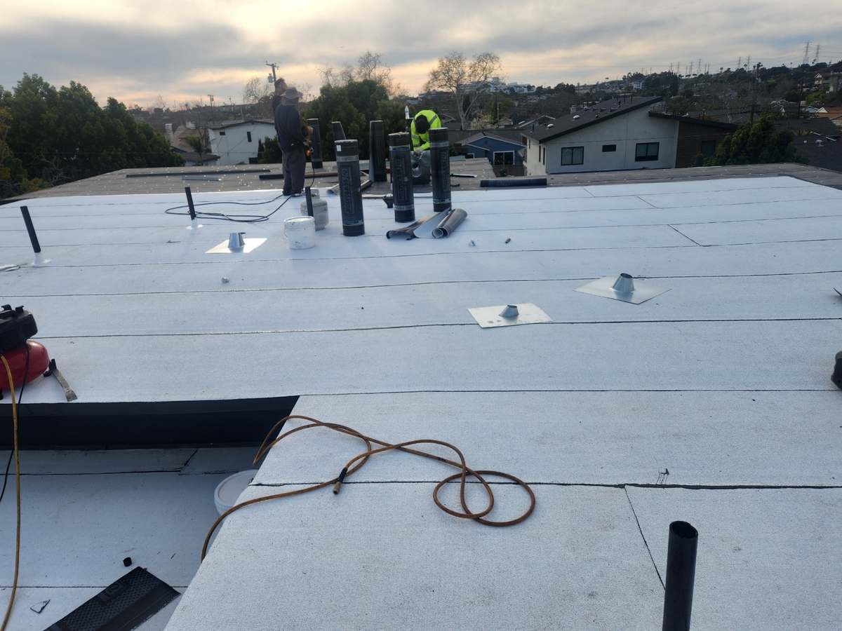 Reflective white cap sheet and pipe flashings on a low-slope roof.