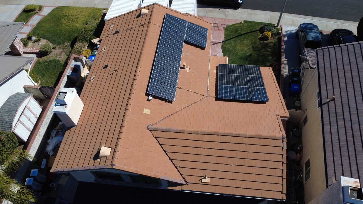 Brown tile roof slopes seen from above with two dark solar panel arrays and vents