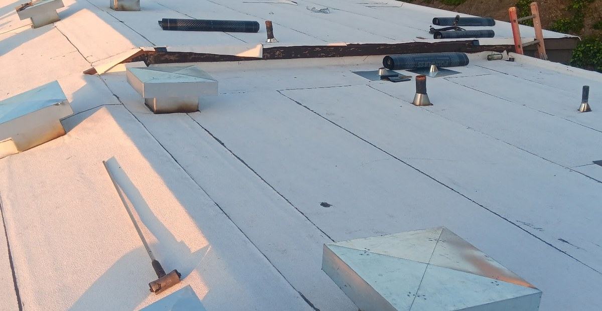 White membrane roof with vents, membrane rolls and tools laid out for work