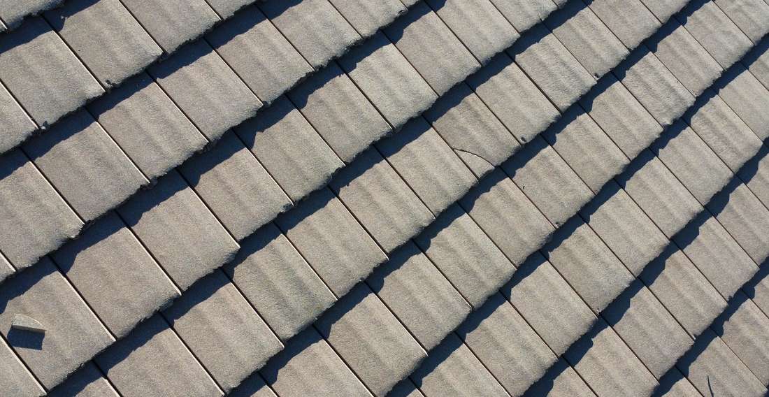 Field of gray textured overlapping roof tiles seen close up