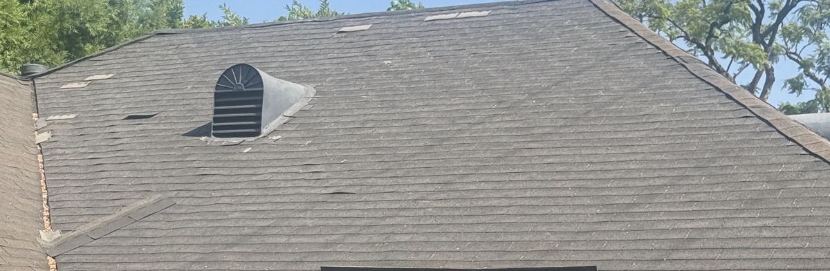 Weathered shingle slope with a roof vent and missing shingle sections.